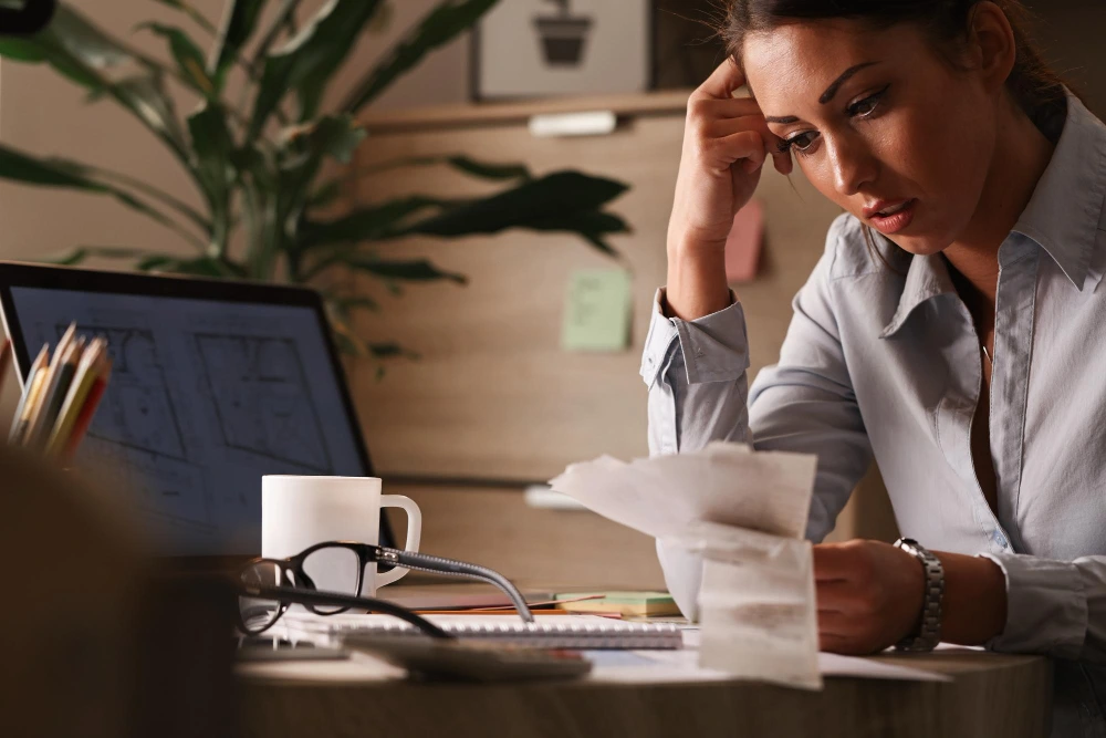 Mujer preocupada revisando documentos financieros en una oficina, representando experiencias de ley de segunda oportunidad.