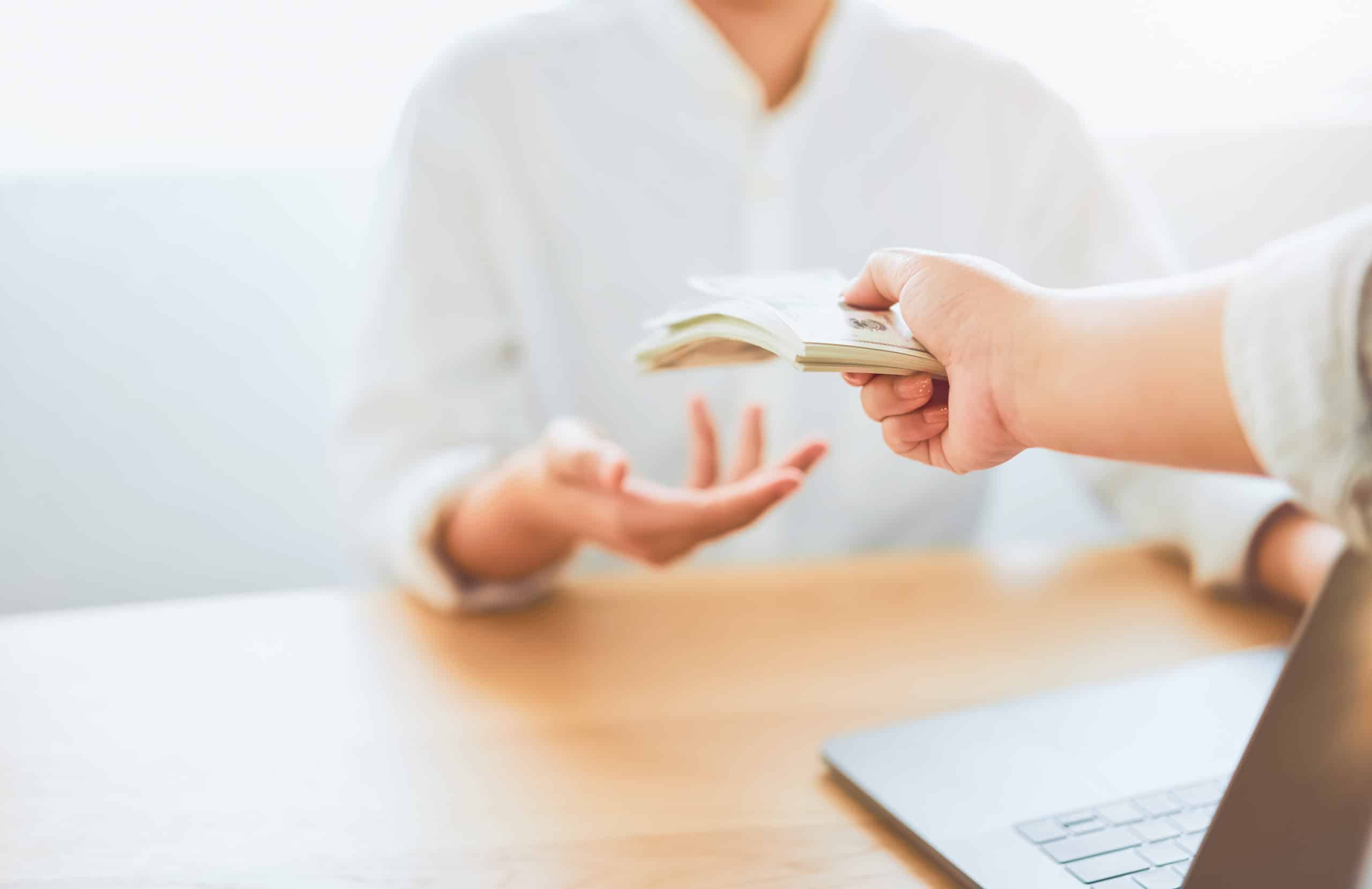 Mujer recibiendo dinero en un banco preguntando por la suplantación de identidad y si puede alguien pedir un crédito a mi nombre