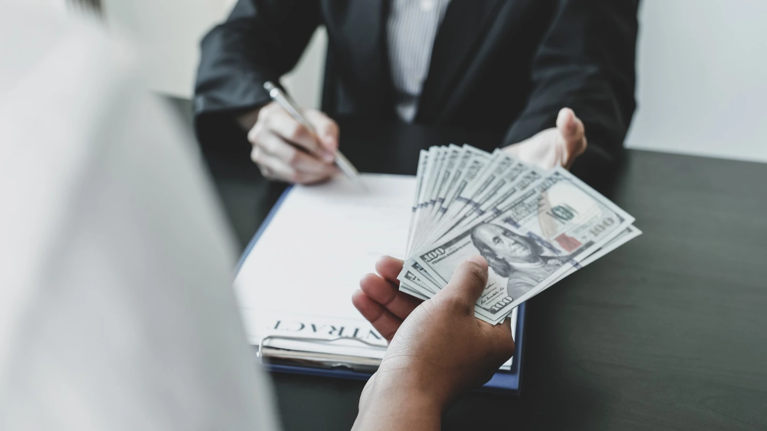 es buena idea pedir un préstamo para pagar otro: entrega de dinero y firma de contrato de préstamo en una mesa