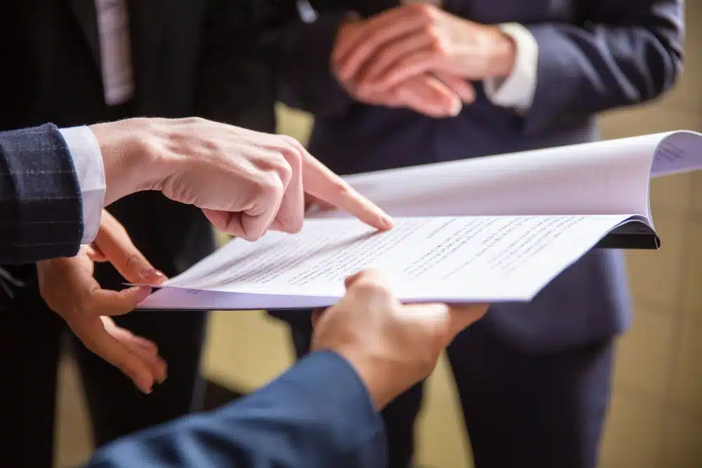 Personas revisando documentos legales en una reunión, ilustrando qué es un juicio monitorio y sus consecuencias si no puedes pagar la deuda.