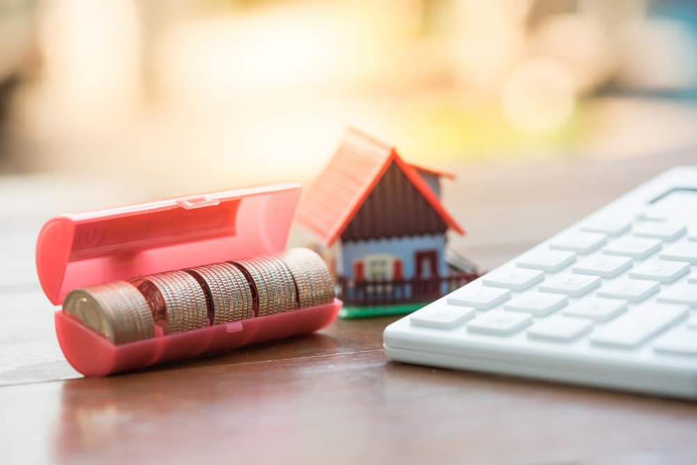 Teclado de ordenador con monedas y una casita de juguete simbolizando el embargo de tu vivienda tras una ejecución hipotecaria.