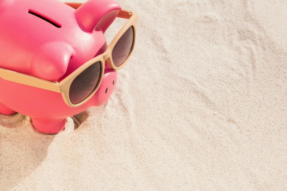 Cerdito hucha en la playa que simboliza prestamo para vacaciones