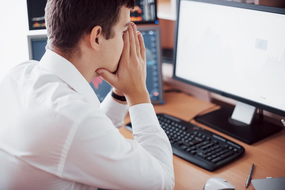 hombre sentado en la mesa de escritorio de una oficina desesperado porque ha sufrido un ataque de spear phishing