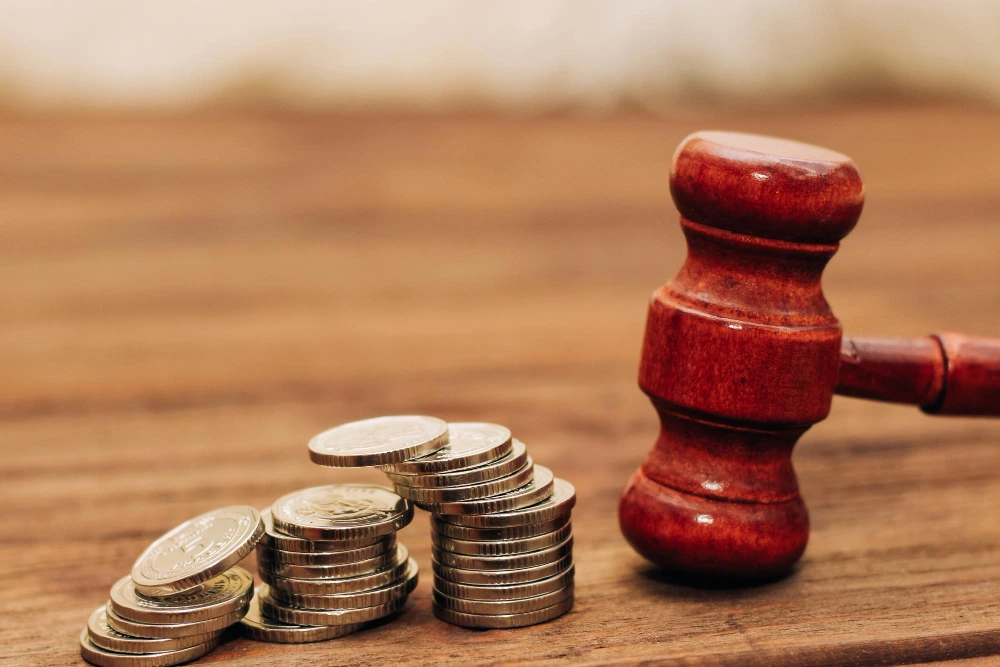 Martillo judicial junto a monedas apiladas, ilustrando la duda frecuente sobre si es delito no pagar un préstamo personal y sus posibles consecuencias legales.