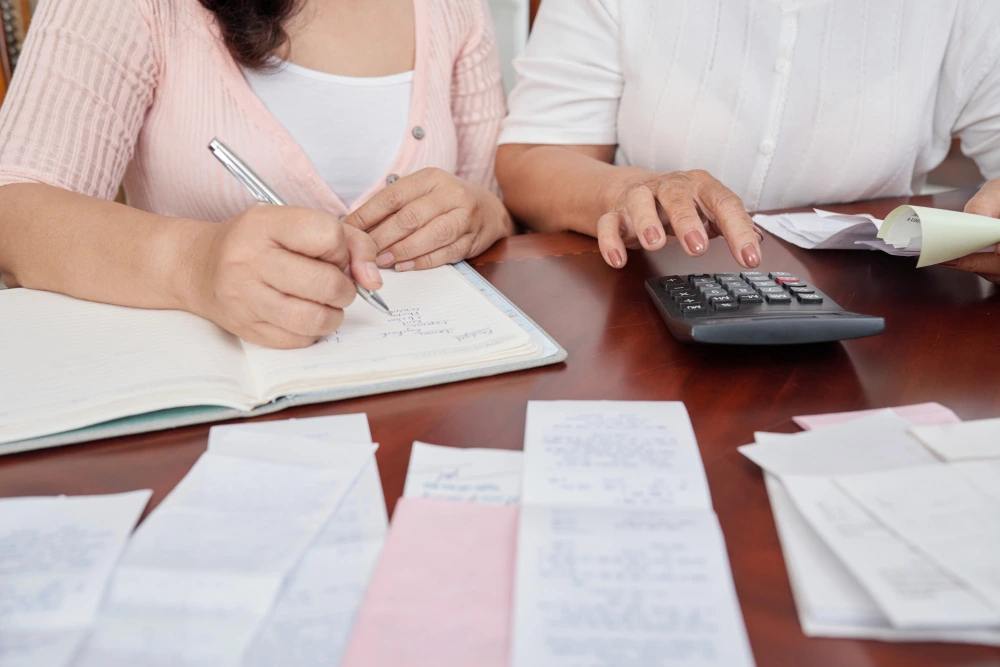 dos personas revisando facturas y usando una calculadora para reunificar deudas