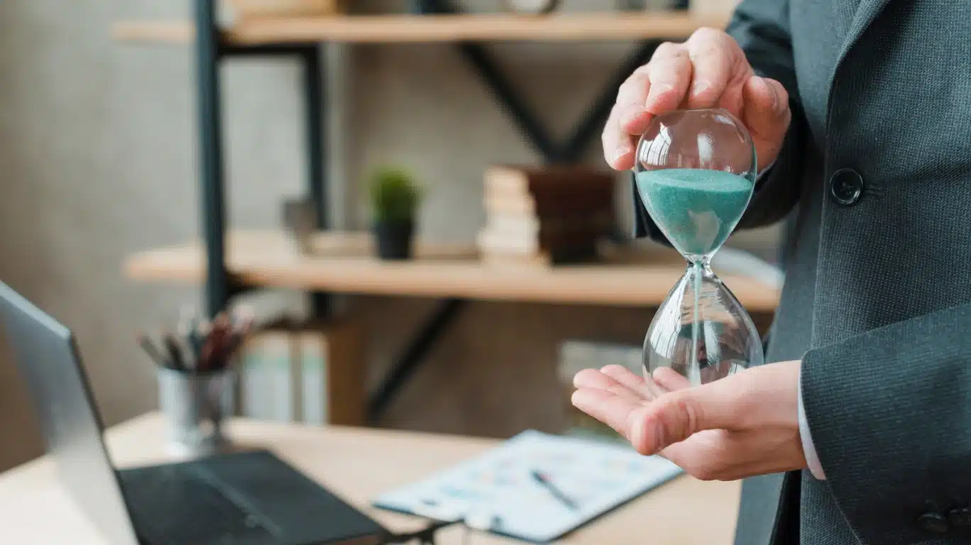 Persona en traje sosteniendo un reloj de arena, simbolizando el tiempo y la espera para entender a partir de qué fecha se puede reclamar el IRPH de la hipoteca, clave para afectados por este índice hipotecario.