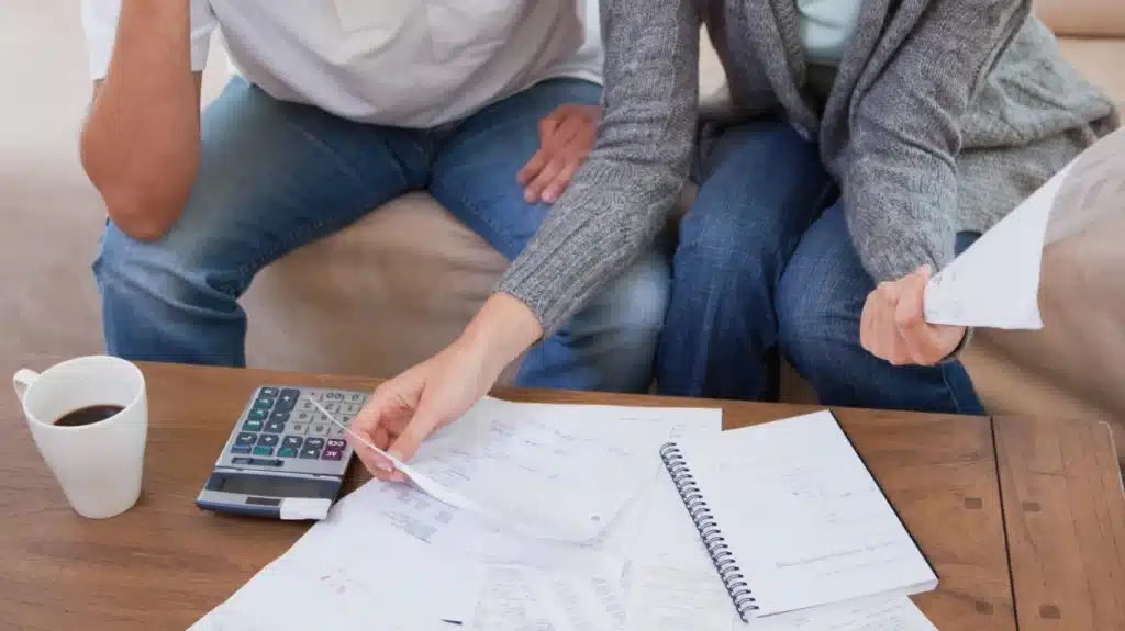 Pareja revisando documentos y calculadora, analizando información financiera sobre IRPH.