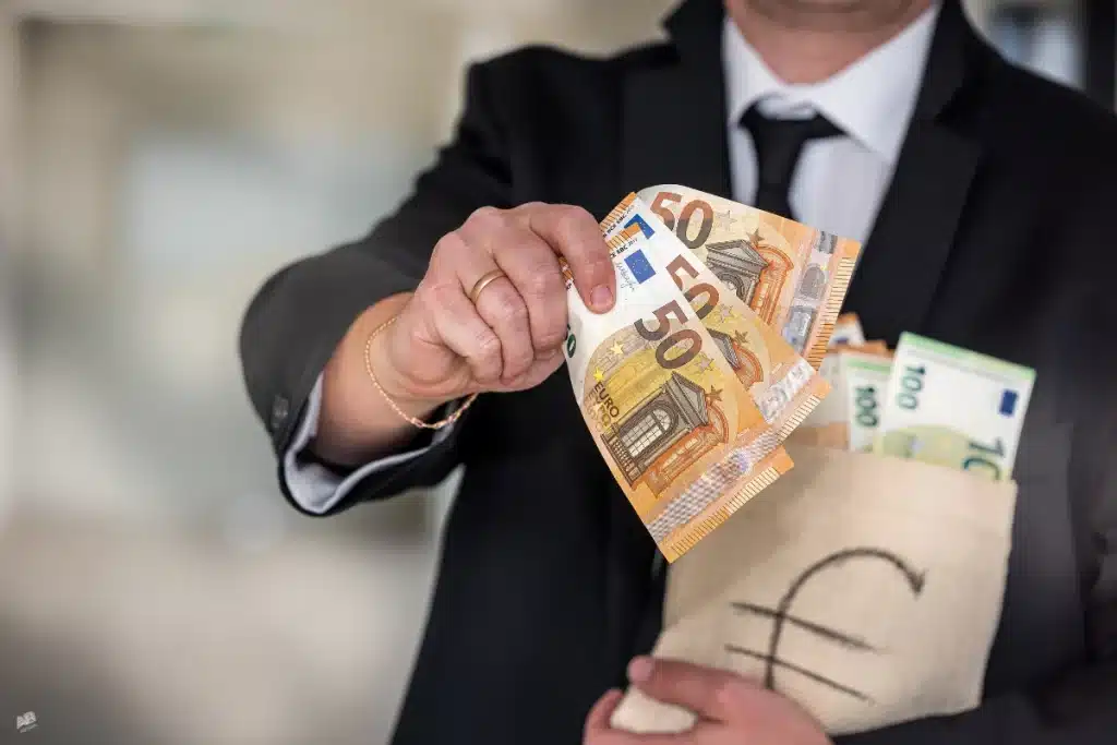 Hombre con traje sosteniendo billetes de euro y una bolsa de dinero, representando la 'prescripción de un préstamo personal'.