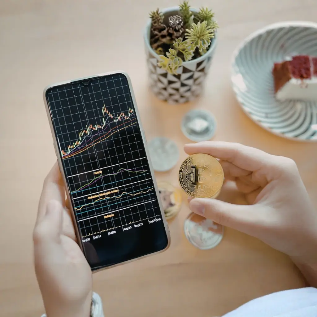 Persona revisando gráficos de inversión en criptomonedas en el móvil, representando cómo saber si estás ante una estafa con criptomonedas.