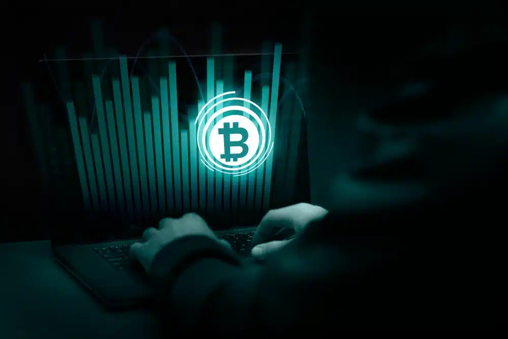 Dos manos de una persona frente a una pantalla virtual con el logo de bitcoin que ha sufrido la estafa criptomonedas