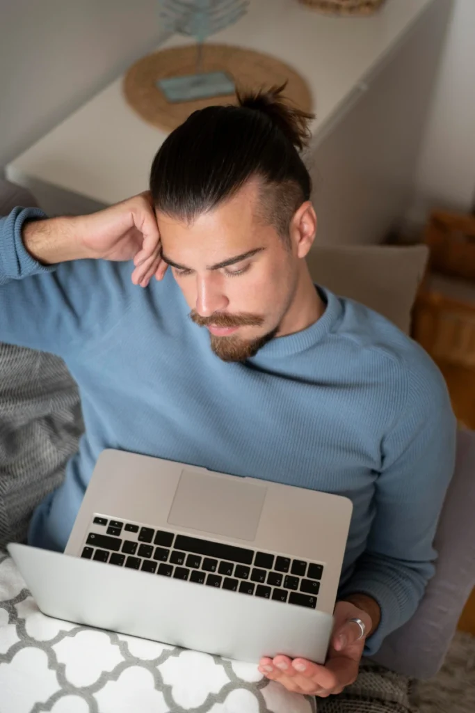 Hombre preocupado usando su portátil desde casa, buscando en internet dónde denunciar una compra online fraudulenta en Barcelona.