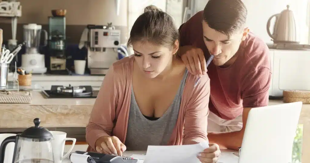Pareja revisando documentos financieros en casa, ilustrando el concepto de tributación de la dación de pago de deuda entre particulares.