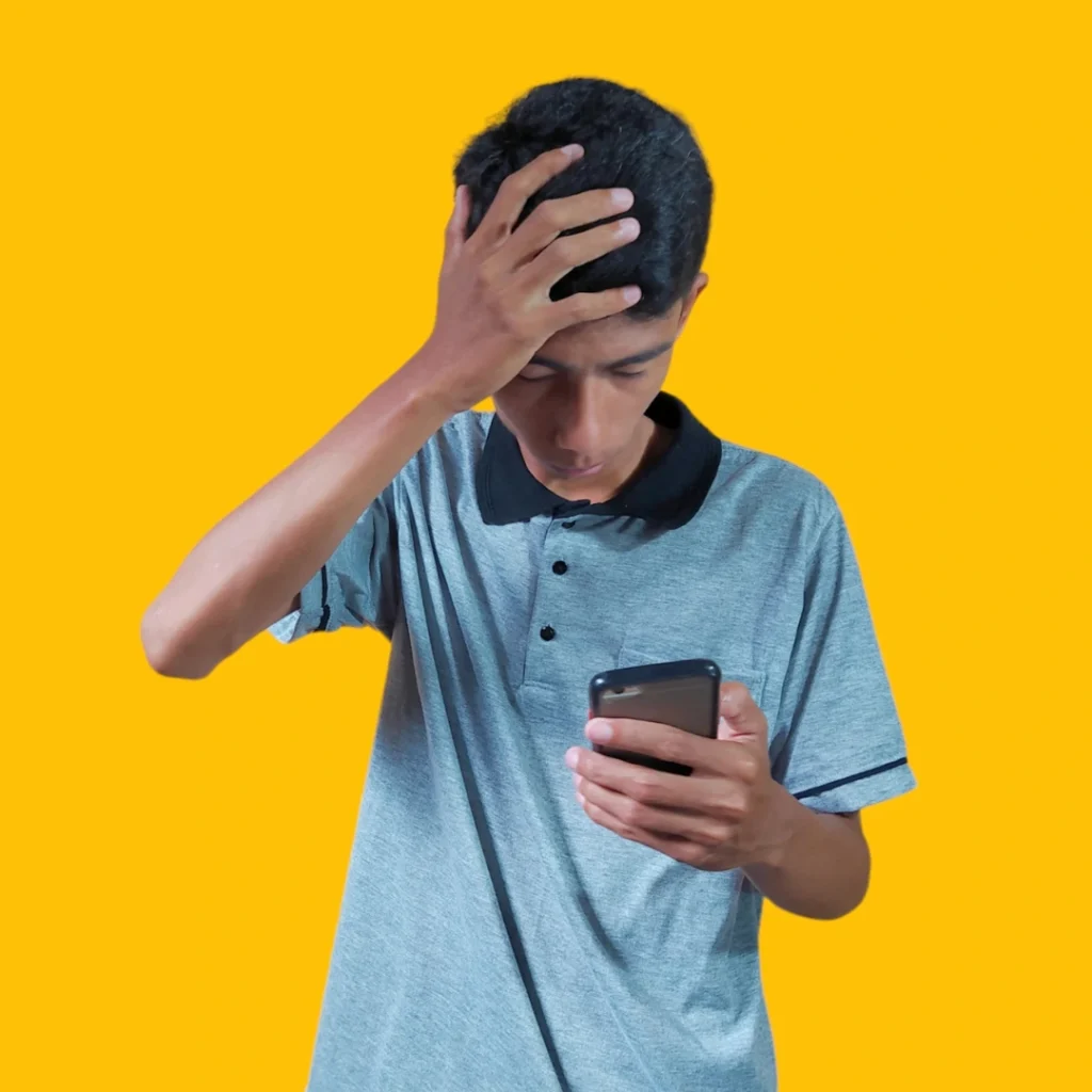 Joven preocupado mirando su teléfono móvil, representando la inquietud de alguien que se pregunta qué hacer si sospechas que estás siendo estafado online o por mensaje.