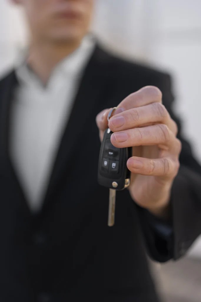 Persona con traje entregando llave de coche, representando el concepto de aval vehicular que es como garantía para acceder a financiación.