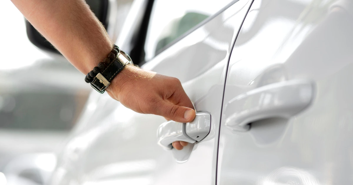 Persona abriendo la puerta de un coche blanco, representando los préstamos con aval de coche rápidos y seguros.