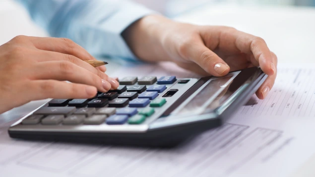 Persona usando una calculadora sobre documentos financieros, representando simulación de hipoteca con calculadora IRPH y análisis de préstamos.