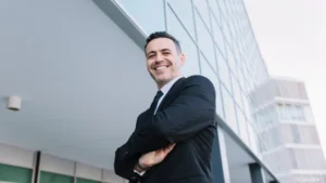 Empresario sonriente con traje frente a edificio corporativo moderno, representando los beneficios de la ley de segunda oportunidad para empresarios en situación de insolvencia.