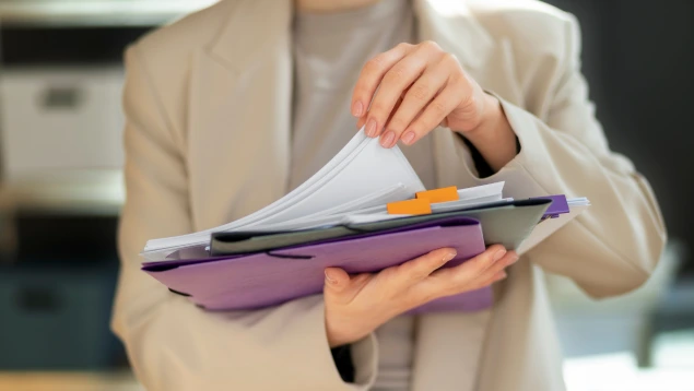 Persona revisando un dossier con documentos etiquetados relacionados con reclamación IRPH en mano, simbolizando el proceso de reclamaciones IRPH judiciales por cláusulas abusivas.