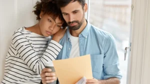 Pareja preocupada revisando documentos financieros, pensando en pedir préstamo sin tarjeta de crédito con cartilla y en alternativas de préstamos solo con cuenta bancaria sin tarjeta de débito.
