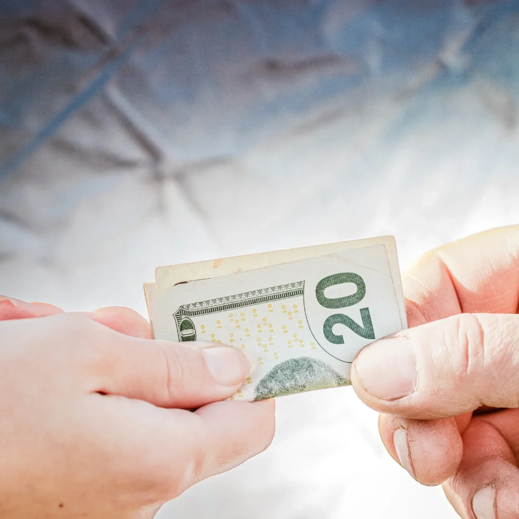 Manos entregando un billete de veinte dólares como símbolo de un préstamo rápido 20 euros en efectivo