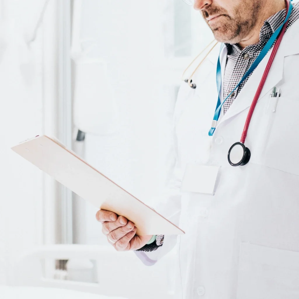 Médico revisando la historia clínica de un paciente en un entorno hospitalario, representando la importancia de elegir el mejor seguro de responsabilidad civil para médicos.