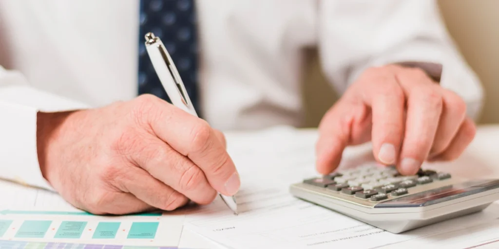 Persona revisando documentos y usando una calculadora para reclamar los gastos de la hipoteca y recuperar el dinero pagado de más al banco.