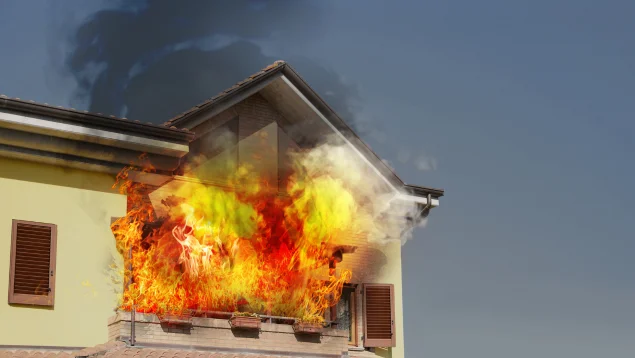 Incendio en una vivienda con el fuego extendiéndose por la fachada y el tejado, representando los daños que deben reclamarse al seguro del hogar tras un siniestro.