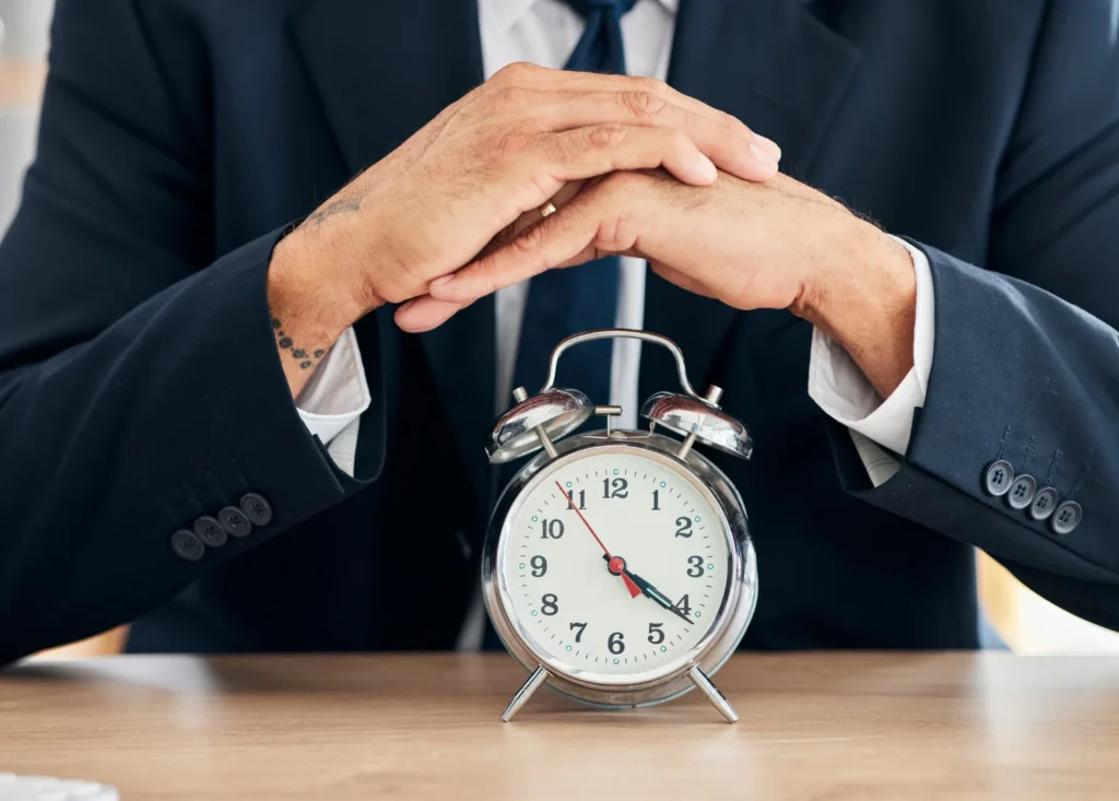 Abogado esperando el plazo procesal con un reloj sobre la mesa, simbolizando el procedimiento de ejecución de títulos no judiciales y los tiempos legales establecidos por la Ley de Enjuiciamiento Civil.