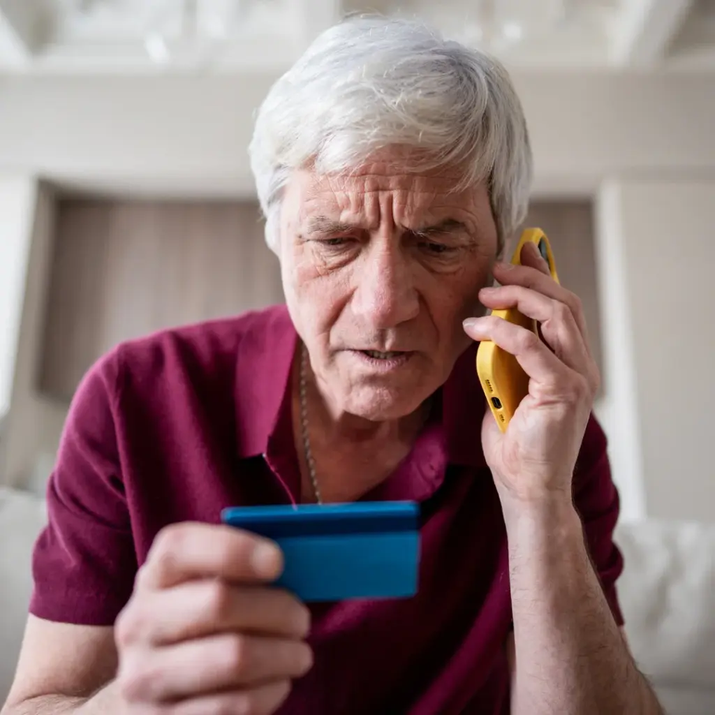 Persona mayor preocupada tras recibir una llamada y revisar una tarjeta por ¿Qué pasa si se filtran mis datos personales? con asesoramiento de Asoban Abogados