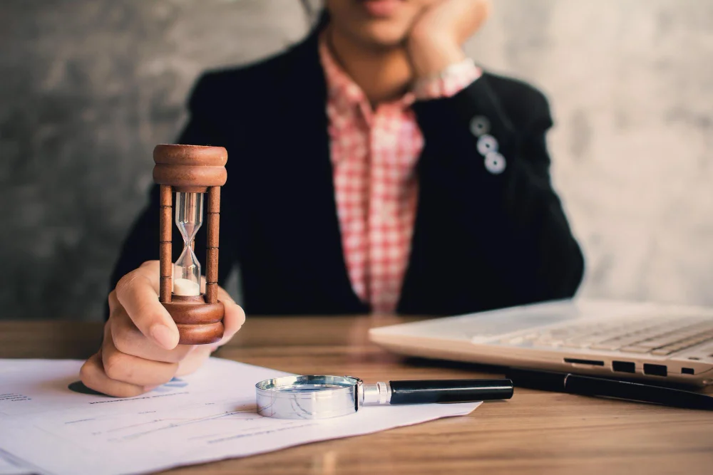 Una persona sostiene un reloj de arena mientras consulta documentos con ayuda de abogados ejecución hipotecaria