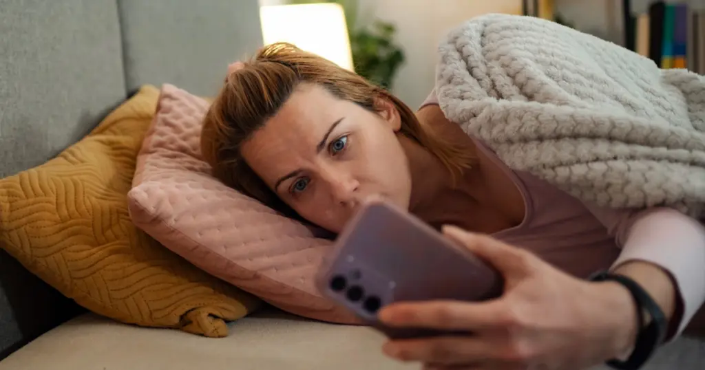Mujer preocupada mirando su móvil tras recibir una llamada sospechosa, representando una estafa telefónica con IA o intento de fraude mediante suplantación de identidad.