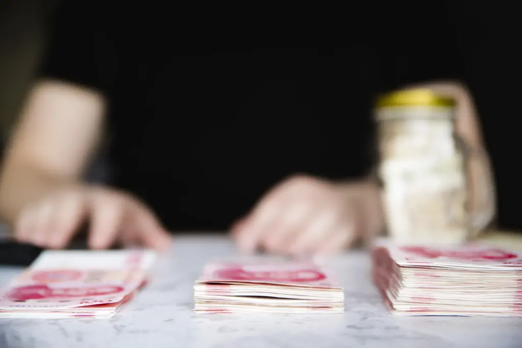 Montones de billetes apilados sobre una mesa oscura con unas manos organizándolos de fondo, ilustrando la reclamación económica y los plazos de un procedimiento monitorio.